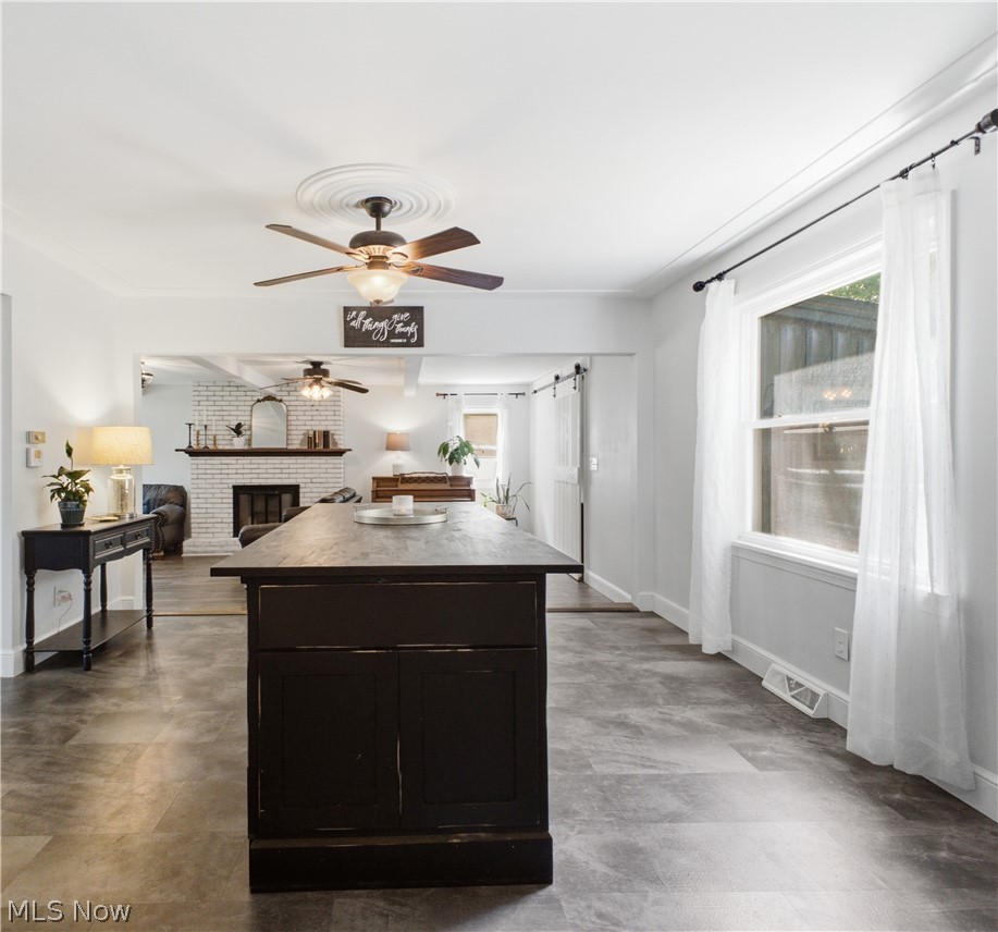 2411 Ridgeview Lane Youngstown, OH 44514 - Photo 11 of 48 Spacious room featuring a dark-finish island with cabinet storage, wood-finish flooring, white walls, and a ceiling fan with decorative medallion