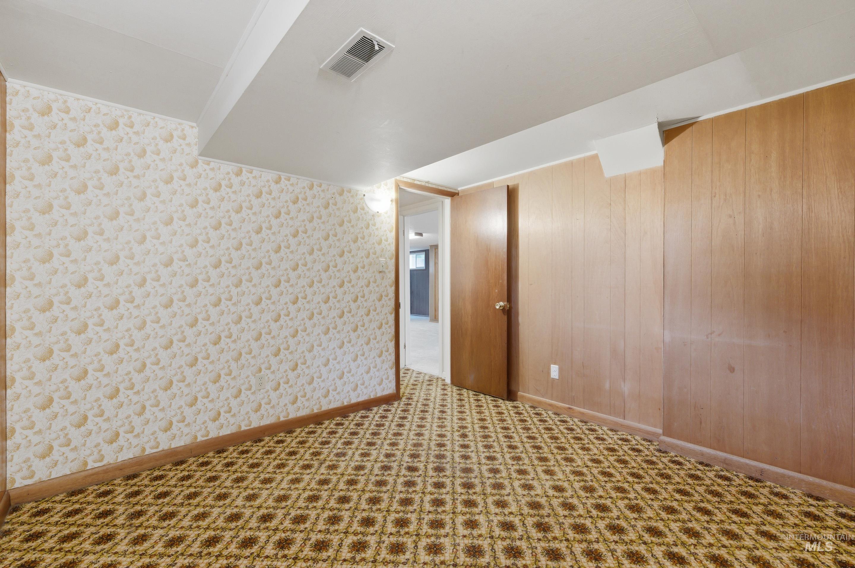 504 West Howe Street Boise, ID 83706 - Photo 34 of 47 Room with patterned carpet flooring, a light-colored accent wall with subtle patterning, and wood paneling on the opposing wall