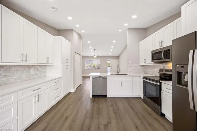 a large kitchen with cabinets wooden floor and stainless steel appliances