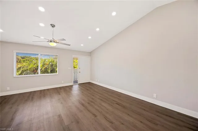 an empty room with wooden floor chandelier and windows