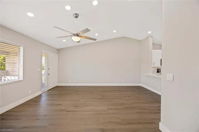 an empty room with wooden floor and windows
