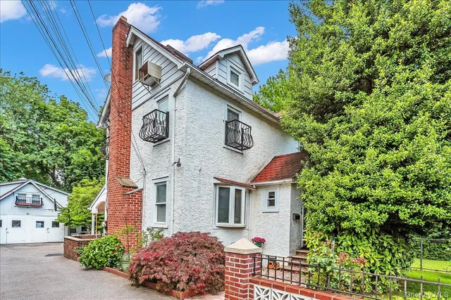 a view of a house with a small yard plants and large tree