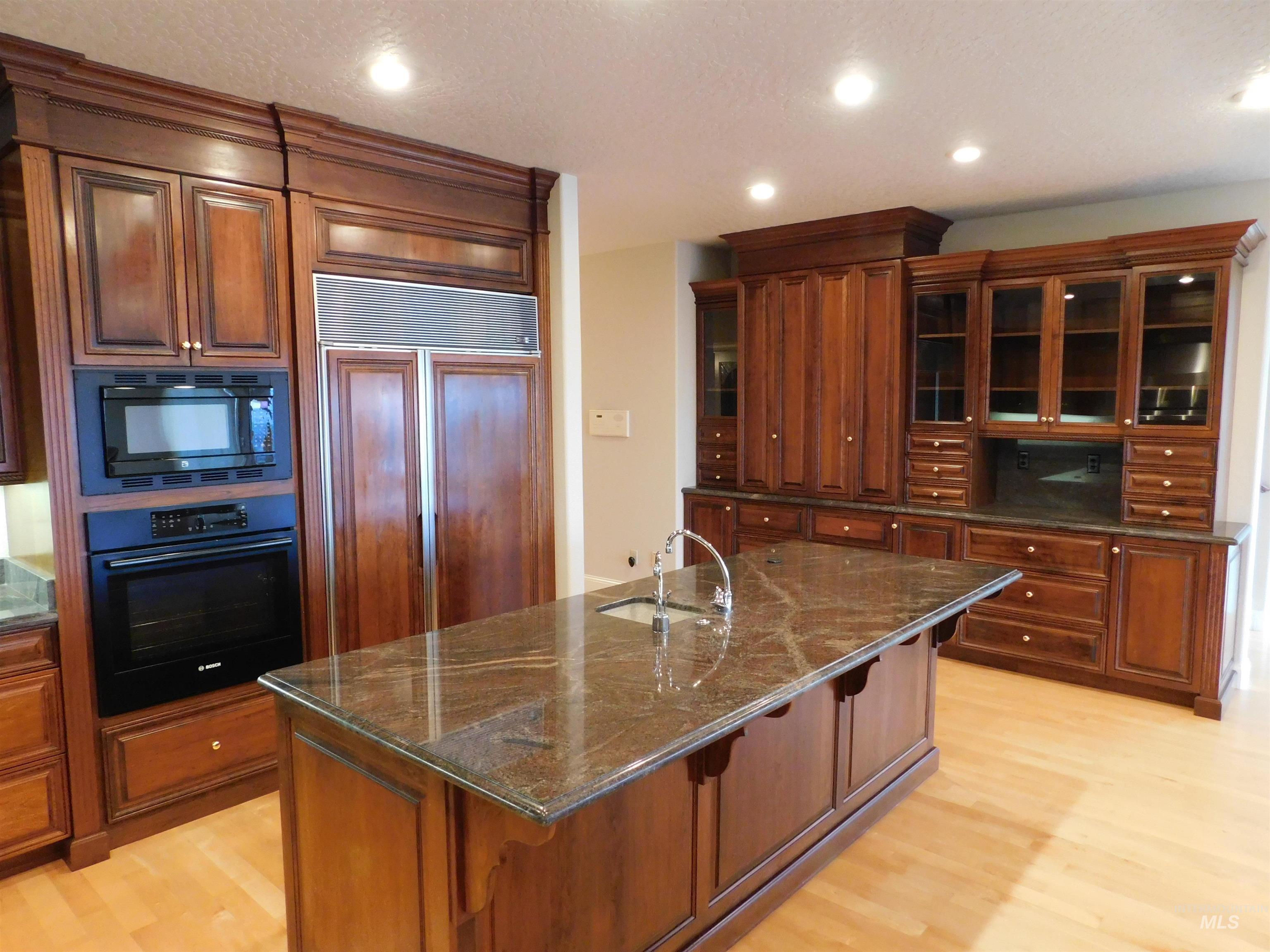 17777 Allendale Road Wilder, ID 83676 - Photo 11 of 50 Kitchen featuring glass insert cabinets, built in appliances, dark stone counters, a kitchen bar, and hardwood floors