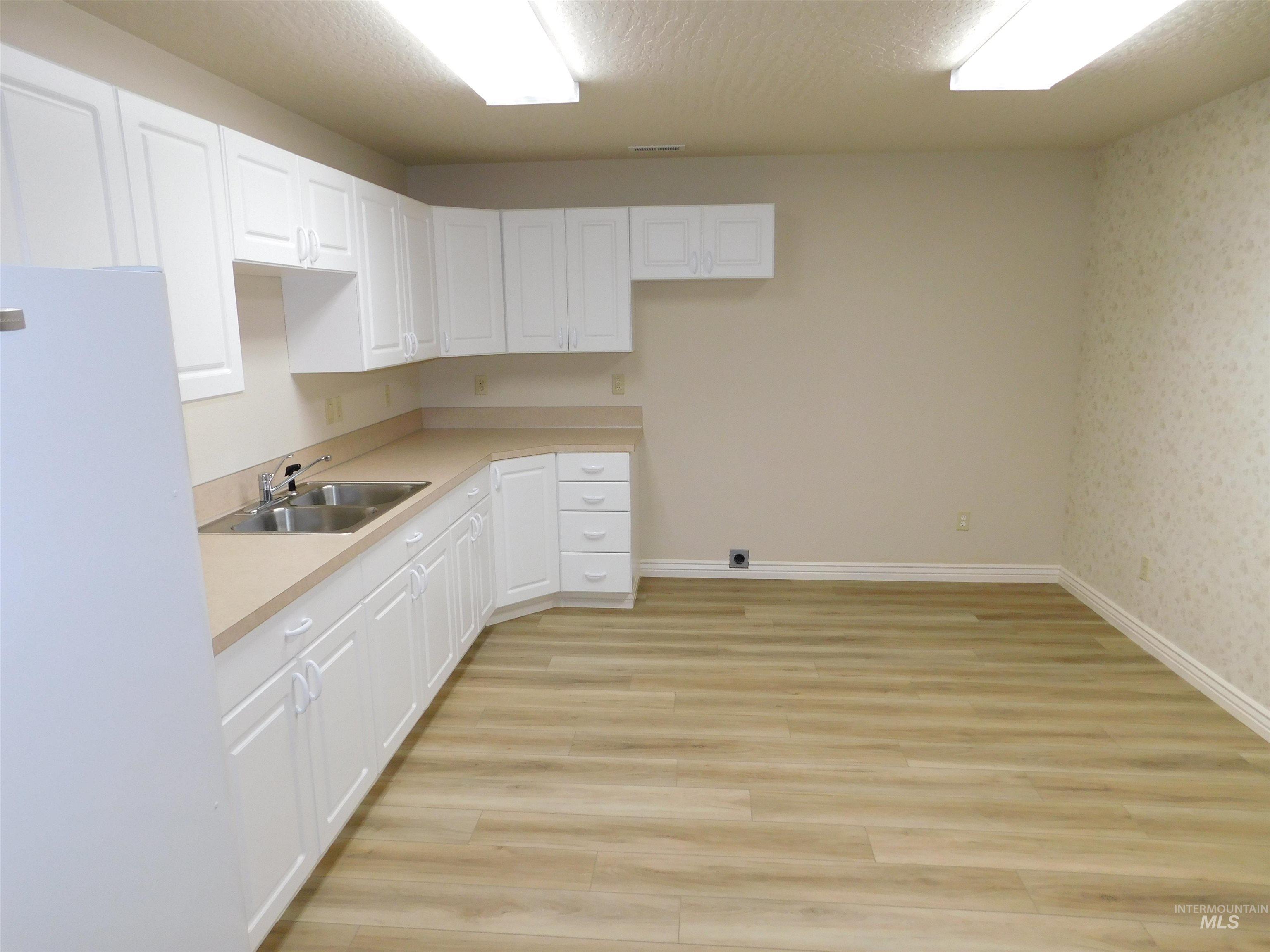 17777 Allendale Road Wilder, ID 83676 - Photo 24 of 50 Kitchen with freestanding refrigerator, light countertops, white cabinets, a textured ceiling, and LVP flooring