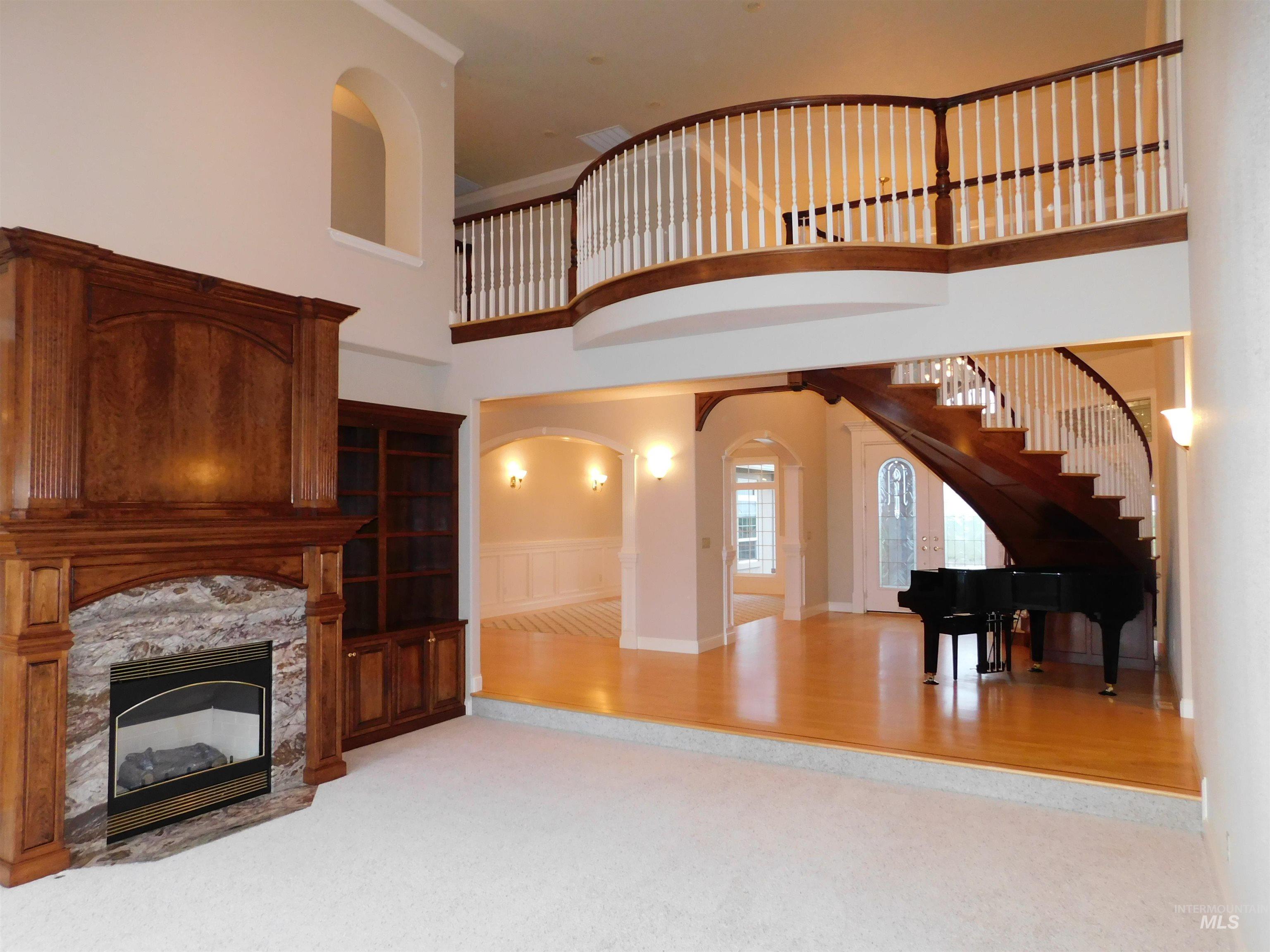 17777 Allendale Road Wilder, ID 83676 - Photo 7 of 50 High ceilings, a glass covered fireplace, arched walkways, light colored carpet, and wainscoting
