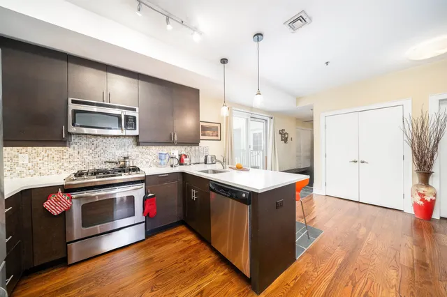 a kitchen with stainless steel appliances granite countertop a sink a stove and a wooden floors