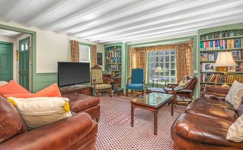 a living room with furniture a bookshelf and a large window