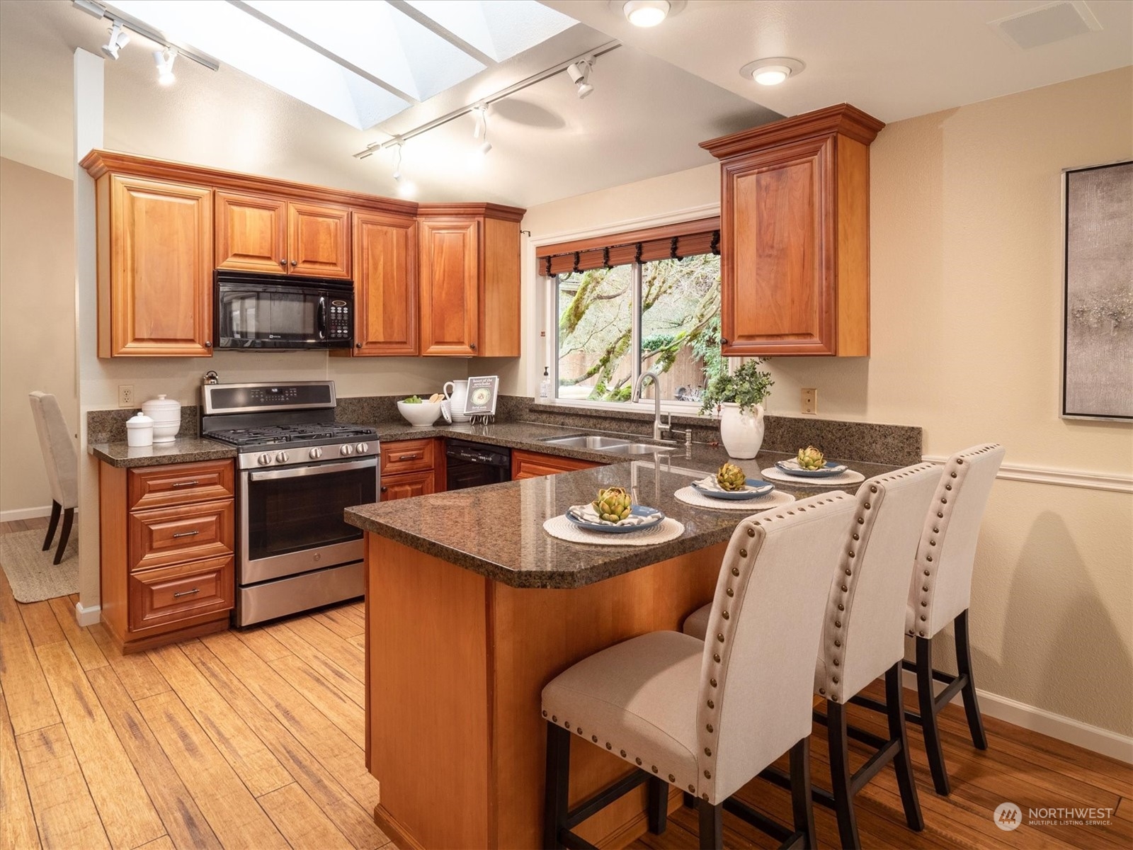 1622 243rd Place Southeast Bothell, WA 98021 - Photo 9 of 25 a kitchen with stainless steel appliances granite countertop a stove top oven a sink dishwasher a dining table and chairs with wooden floor