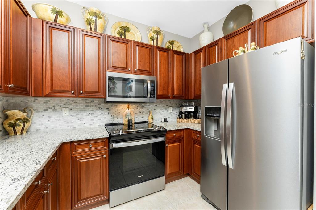 17094 Acapulco Road, Unit 321 Punta Gorda, FL 33955 - Photo 8 of 52 a kitchen with granite countertop a refrigerator stove and microwave
