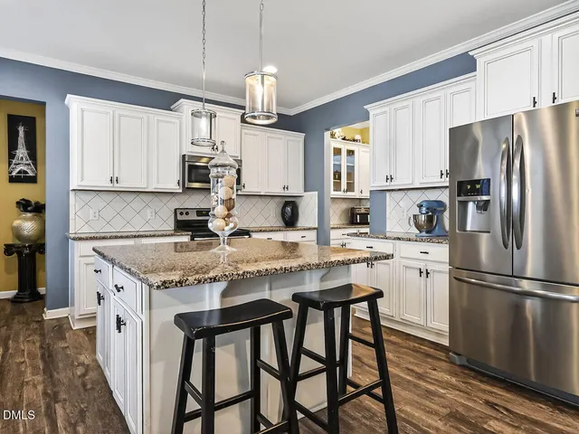 a kitchen with stainless steel appliances granite countertop a table chairs sink refrigerator and cabinets