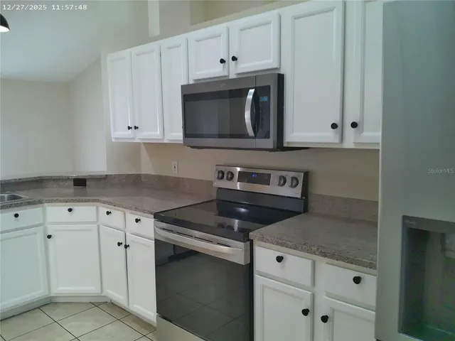 a kitchen with white cabinets and black appliances