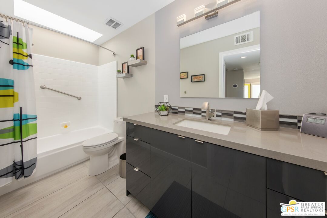 36022 Paseo Circulo West Cathedral City, CA 92234 - Photo 26 of 47 a bathroom with a granite countertop sink a toilet a mirror and bathtub