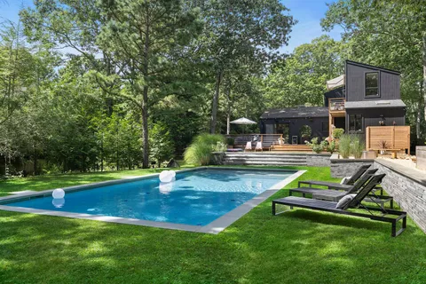 a view of backyard with swimming pool and trees