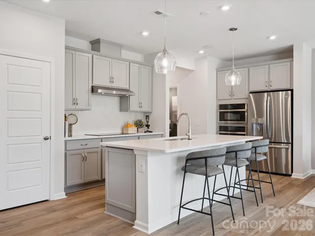 a kitchen with stainless steel appliances granite countertop a sink a stove a refrigerator and island with wooden floor