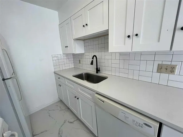 a kitchen with white cabinets and sink