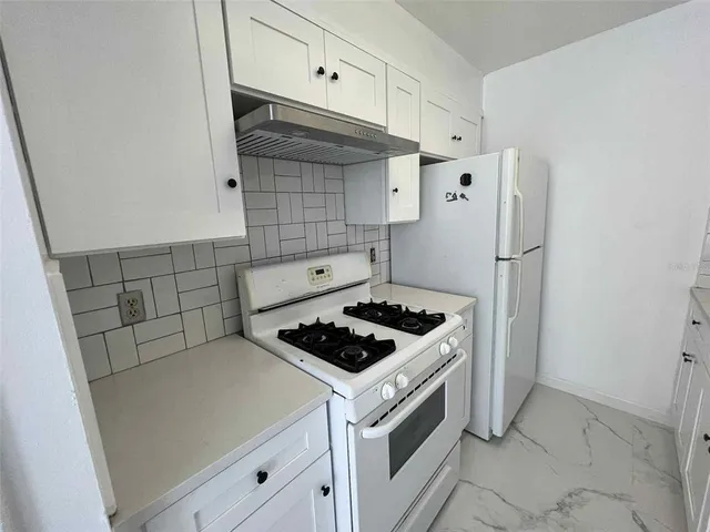 a kitchen with white cabinets and white stove