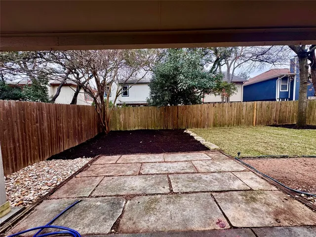 a view of backyard with large trees and wooden fence