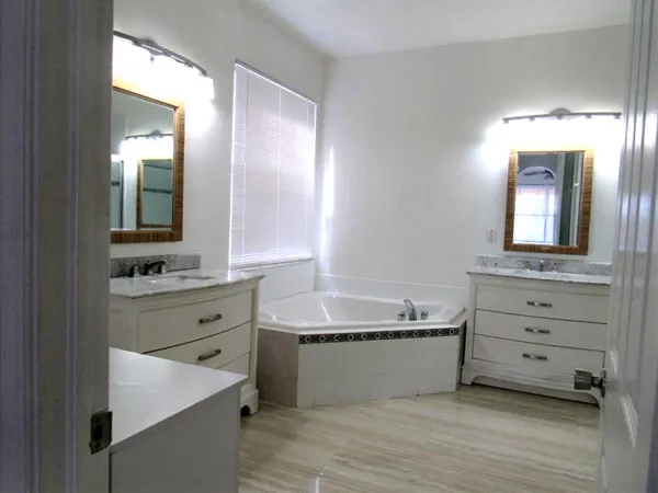 a bathroom with a double vanity sink mirror and bathtub