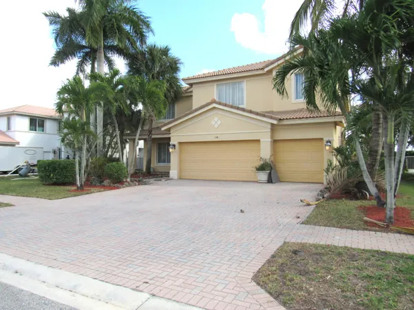 front view of a house with a yard and palm trees