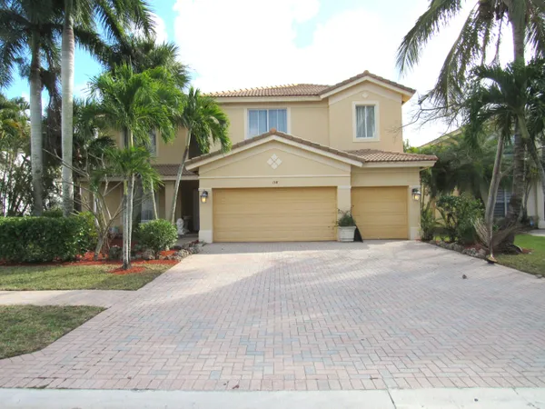 front view of a house with a yard and palm trees