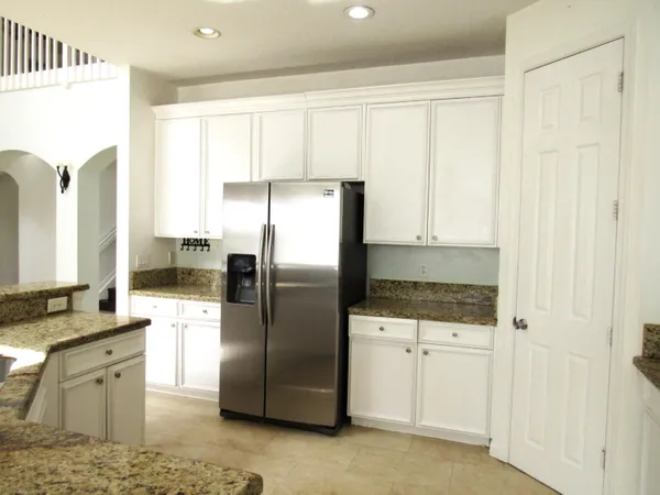 a kitchen with granite countertop white cabinets and refrigerator