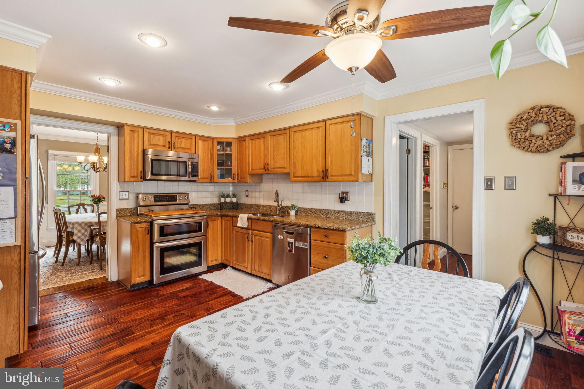 25 Wallingford Way Shamong, NJ 08088 - Photo 17 of 65 a kitchen with stainless steel appliances granite countertop a stove top oven a sink dishwasher a dining table and chairs with wooden floor