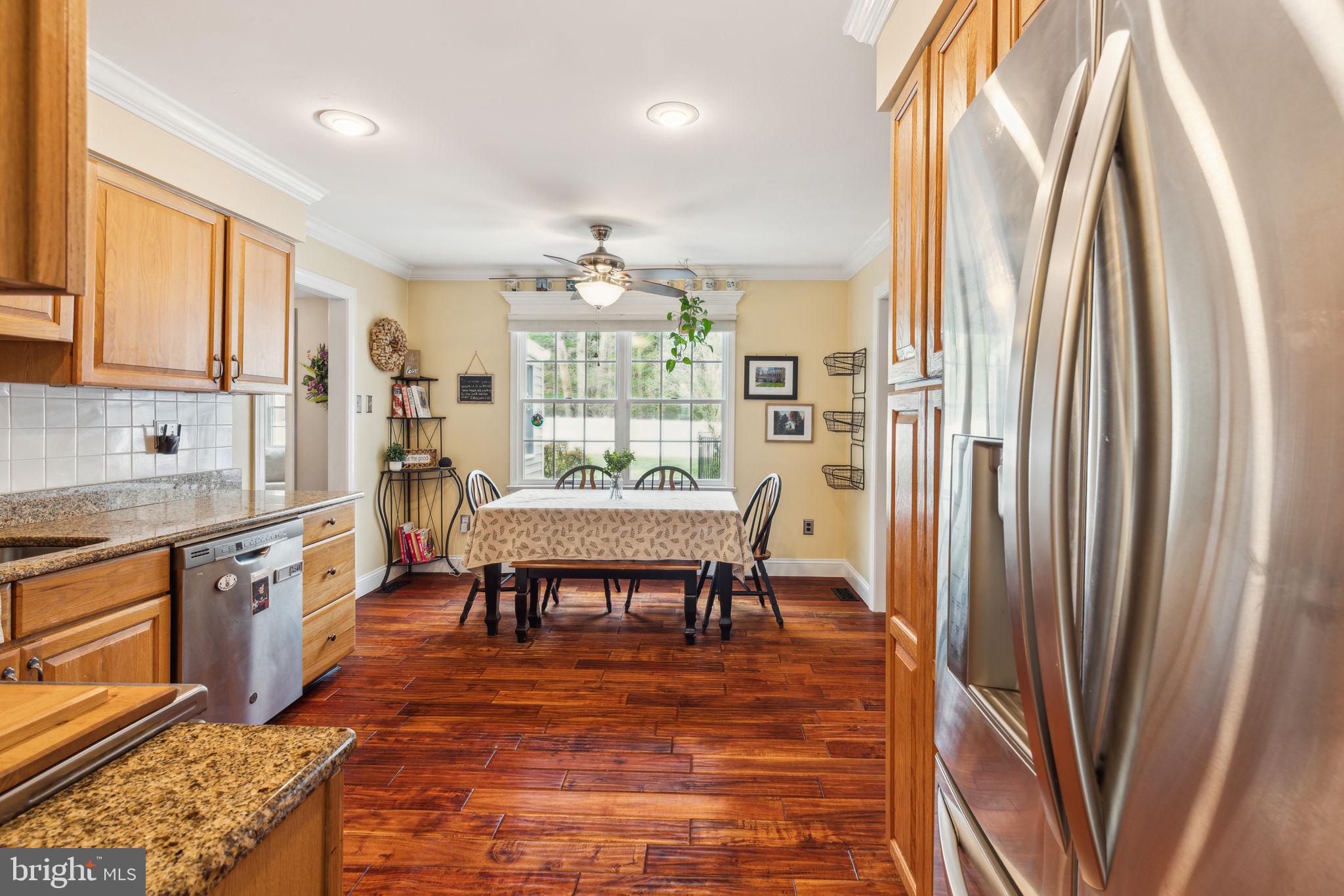 25 Wallingford Way Shamong, NJ 08088 - Photo 22 of 65 a dining room with stainless steel appliances granite countertop a refrigerator a stove a sink dishwasher with a dining table and chairs with wooden floor