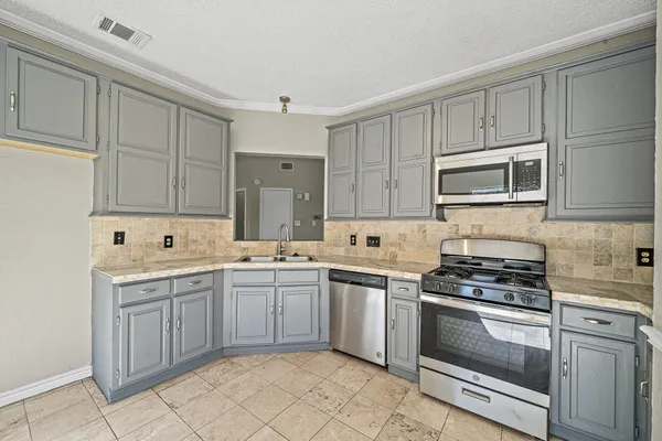 a kitchen with cabinets appliances a sink and a counter top