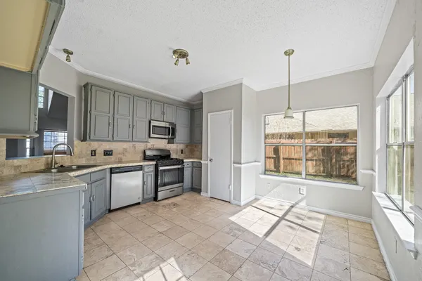 a open kitchen with stainless steel appliances granite countertop a stove top oven a sink dishwasher a dining table and chairs with wooden floor