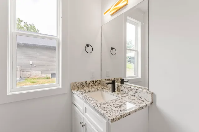 a bathroom with a granite countertop sink and a mirror