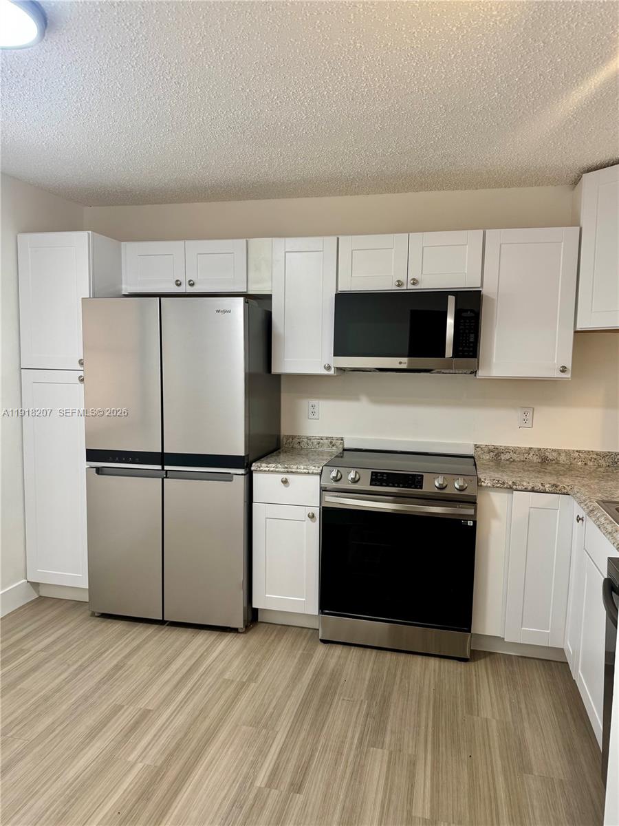 605 Ives Dairy Road, Unit 3067 Miami, FL 33179 - Photo 4 of 28 a kitchen with stainless steel appliances granite countertop a stove a sink and a microwave