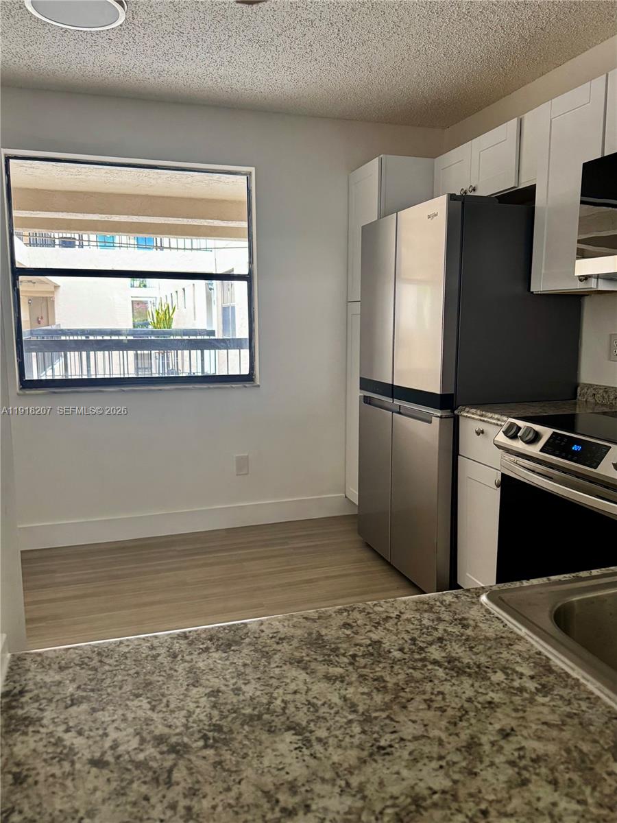 605 Ives Dairy Road, Unit 3067 Miami, FL 33179 - Photo 6 of 28 a kitchen with granite countertop a refrigerator stove and microwave