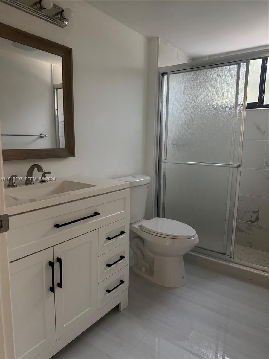 605 Ives Dairy Road, Unit 3067 Miami, FL 33179 - Photo 7 of 28 a bathroom with a toilet a sink a mirror and vanity