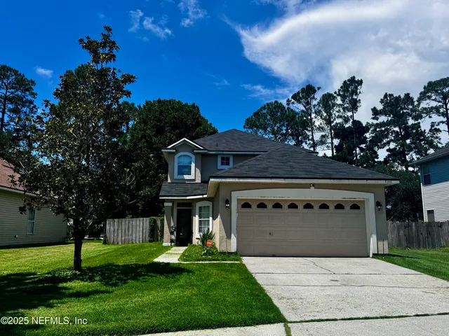 a front view of a house with a garden and trees