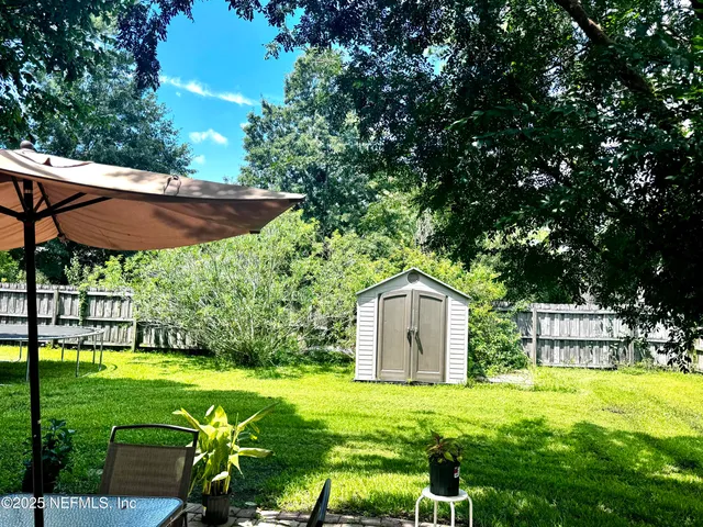 a backyard of a house with table and chairs under an umbrella
