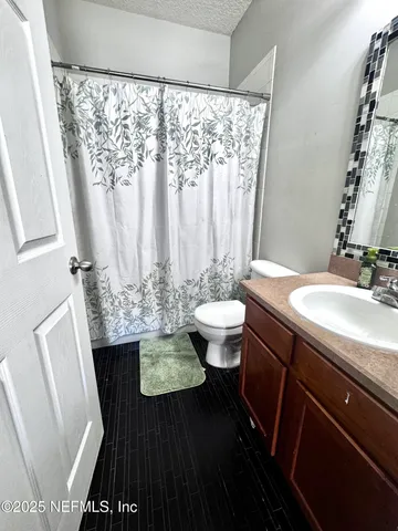 a bathroom with a granite countertop sink toilet a mirror and a shower