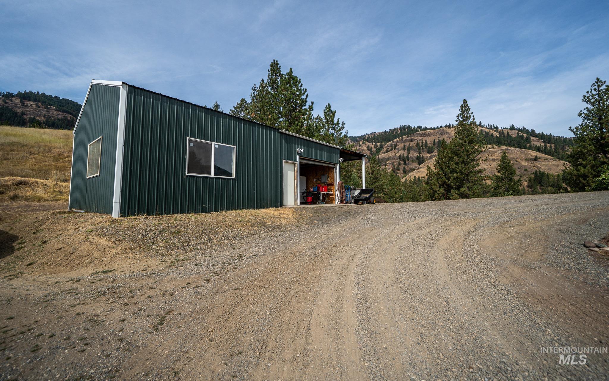 161 Saddle Ridge Road White Bird, ID 83554 - Photo 7 of 49 Green metal-clad outbuilding with a single window, a personnel door, and an open bay