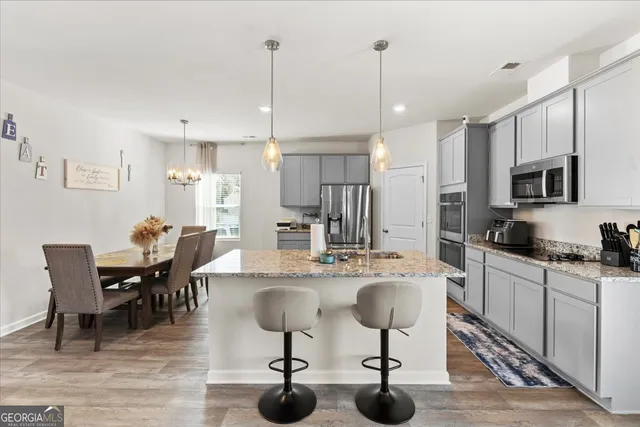 a kitchen with stainless steel appliances kitchen island granite countertop a table chairs sink and cabinets