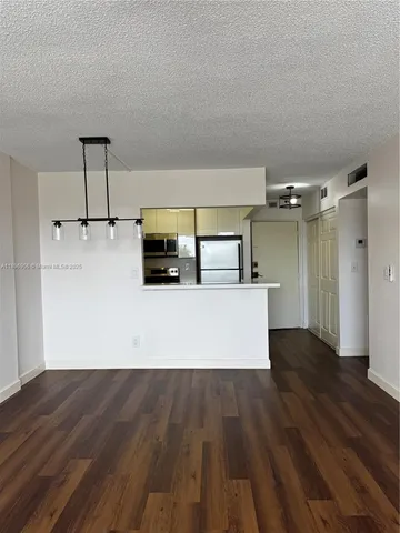 a view of a kitchen with wooden floor and a hallway