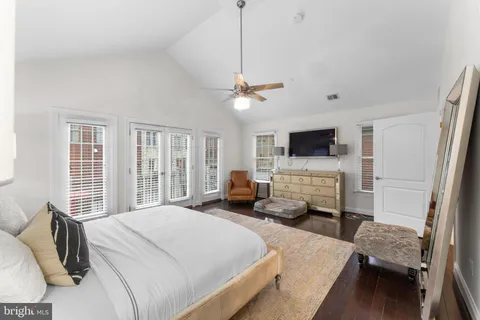 a bedroom with bed a flat tv screen and a dresser