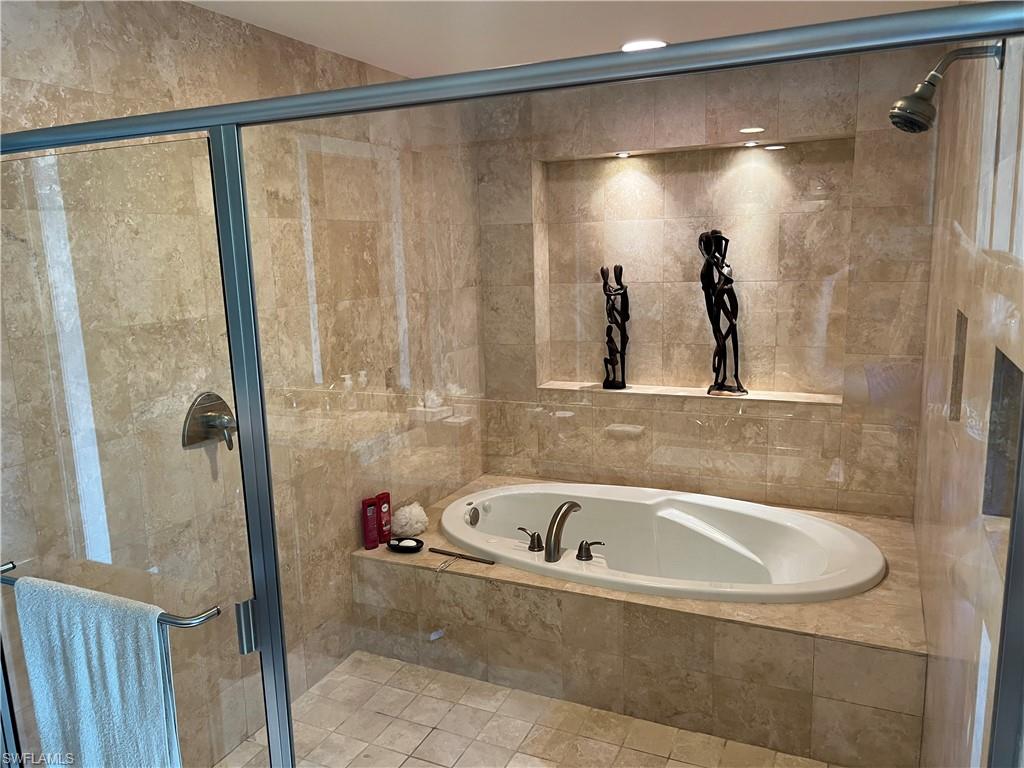 265 Indies Way, Unit 701 Naples, FL 34110 - Photo 18 of 36 a bathroom with a bathtub and a shower