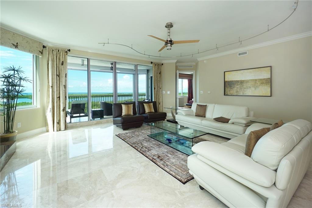 265 Indies Way, Unit 701 Naples, FL 34110 - Photo 3 of 36 a living room with furniture large windows and a chandelier
