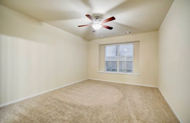 en empty room with ceiling fan and window