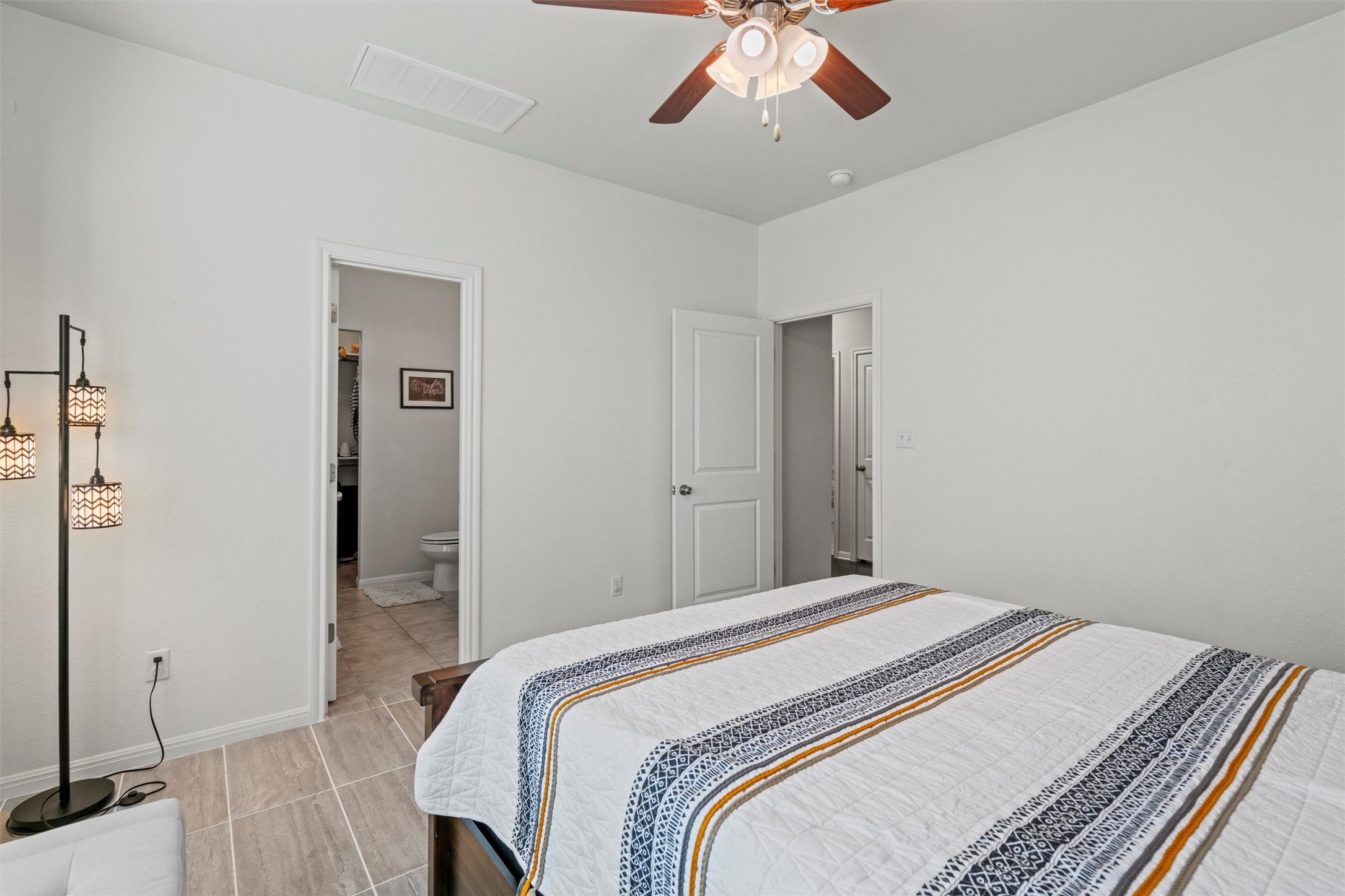 8144 Daisy Cutter Crossing Georgetown, TX 78626 - Photo 13 of 40 Bedroom featuring ensuite bathroom, light tile patterned floors, baseboards, visible vents, and ceiling fan