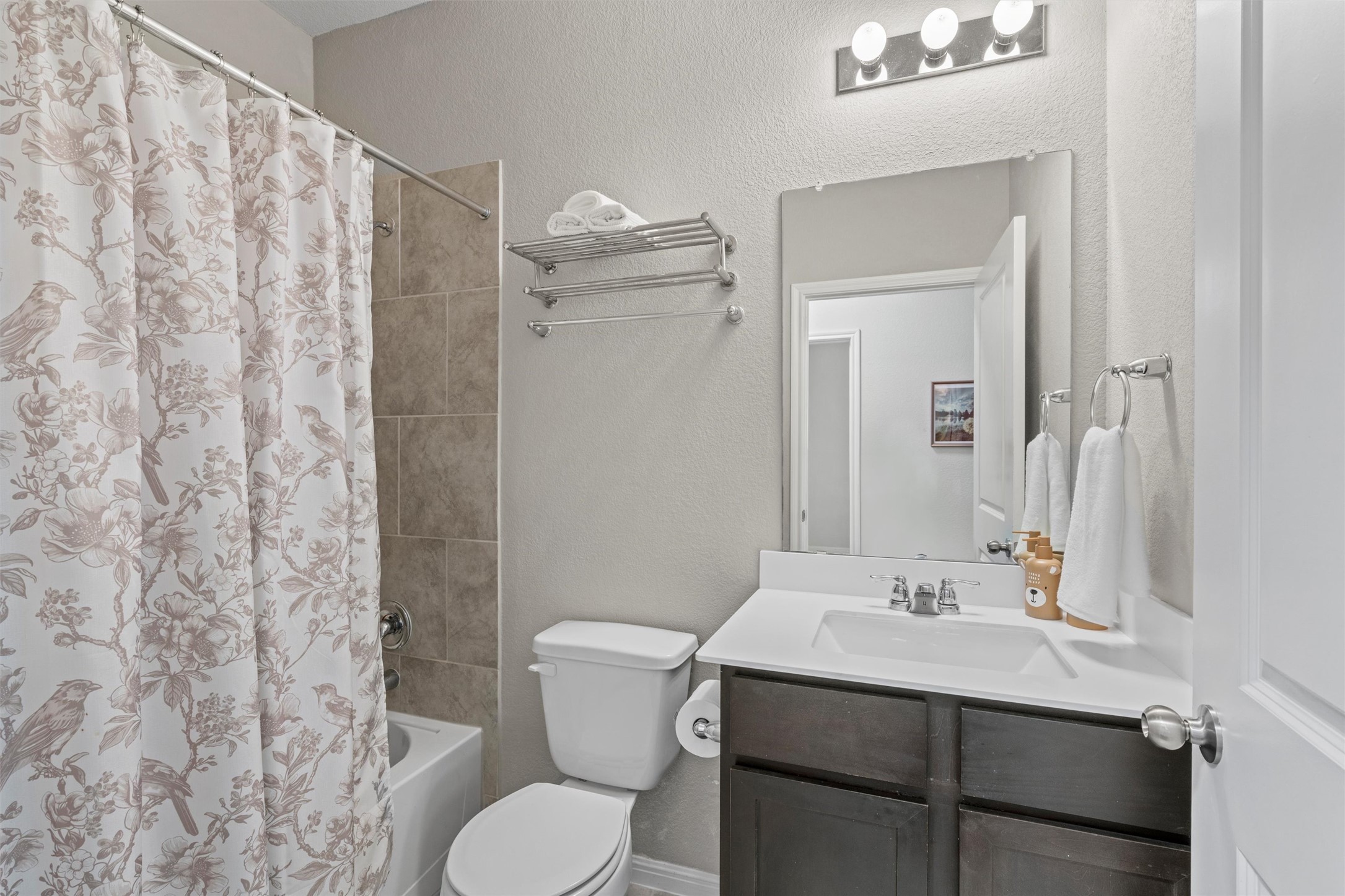 8144 Daisy Cutter Crossing Georgetown, TX 78626 - Photo 19 of 40 Bathroom featuring a textured wall, toilet, vanity, and shower / bathtub combination with curtain