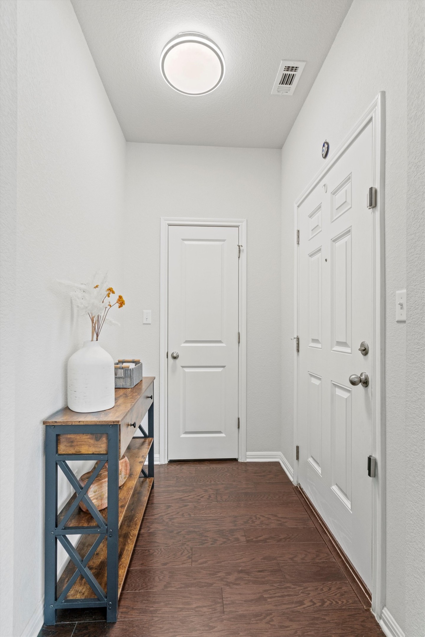 8144 Daisy Cutter Crossing Georgetown, TX 78626 - Photo 3 of 40 Corridor with dark wood-type flooring, baseboards, a textured ceiling, and visible vents