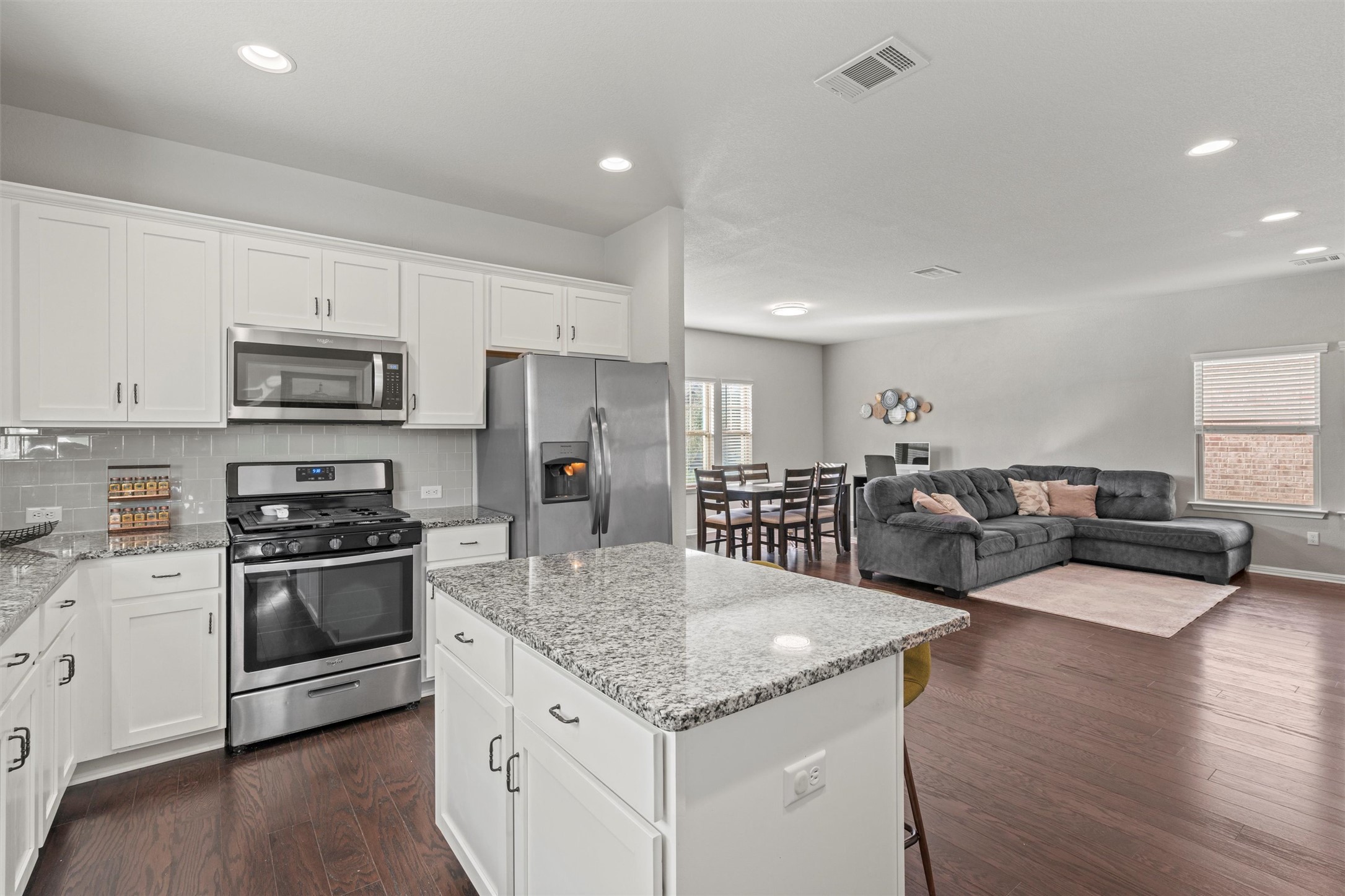 8144 Daisy Cutter Crossing Georgetown, TX 78626 - Photo 10 of 40 Kitchen with visible vents, appliances with stainless steel finishes, dark wood-type flooring, white cabinetry, and backsplash