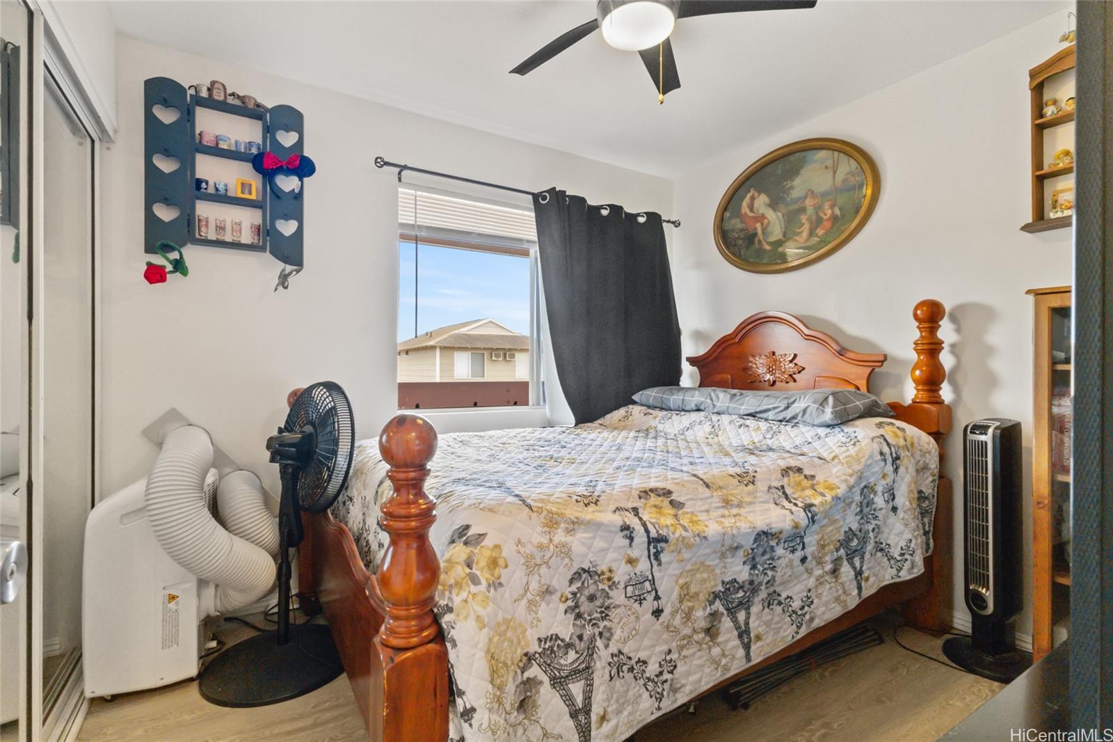 91-1010 Huliau Street, Unit 5C Ewa Beach, HI 96706 - Photo 10 of 16 a bedroom with a bed and a chandelier