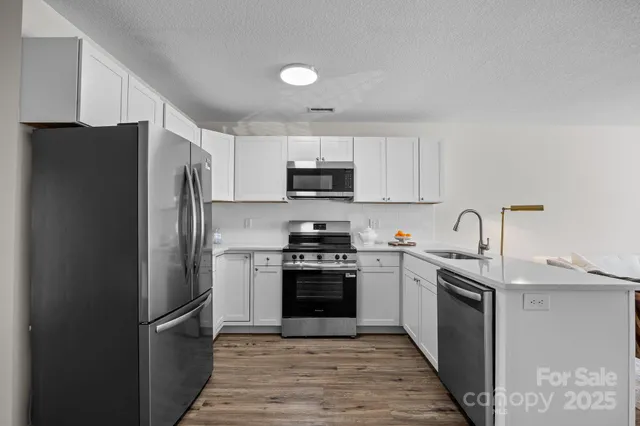 a kitchen with stainless steel appliances granite countertop a refrigerator stove and a sink