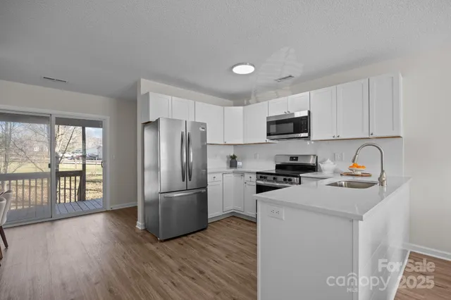 a kitchen with stainless steel appliances granite countertop a refrigerator stove top oven and sink with wooden floor